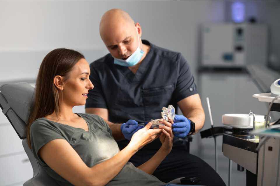 Lekarz pokazuje jak zakłada aparat ortodontyczny